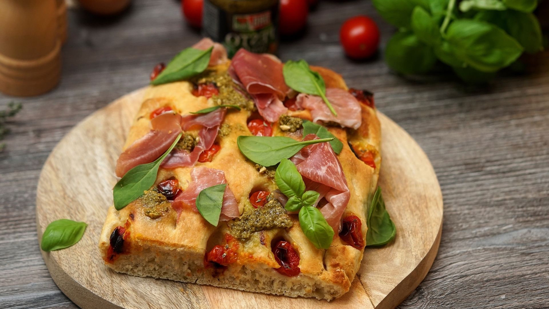 Focaccia mit grünem Pesto und Parma Schinken liegt auf einem Holzbrett