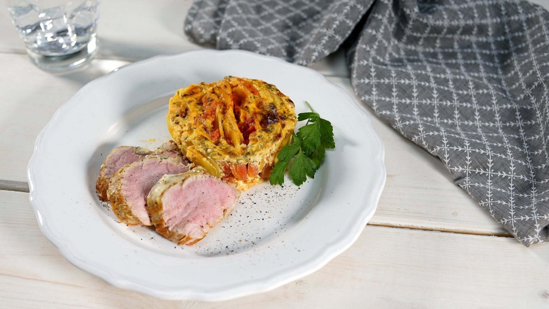Ein Teller mit gratiniertem Schweinefilet und Tomaten-Kartoffel-Gratin