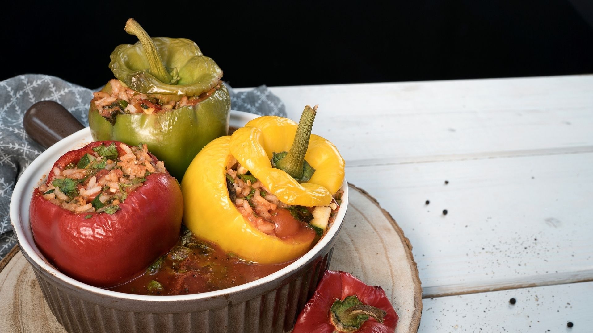 Drei gefüllte Paprikaschoten in einer runden Auflaufform