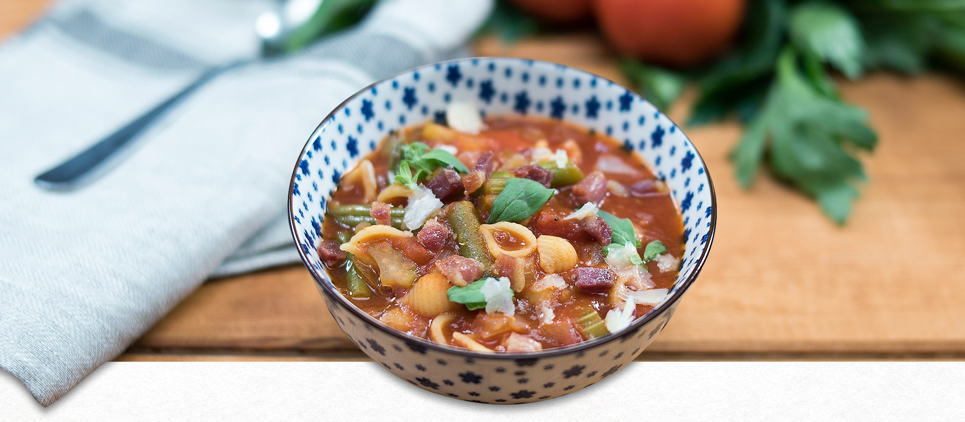 Minestrone in einer blau-weißen Schüssel mit Kräutern dekoriert