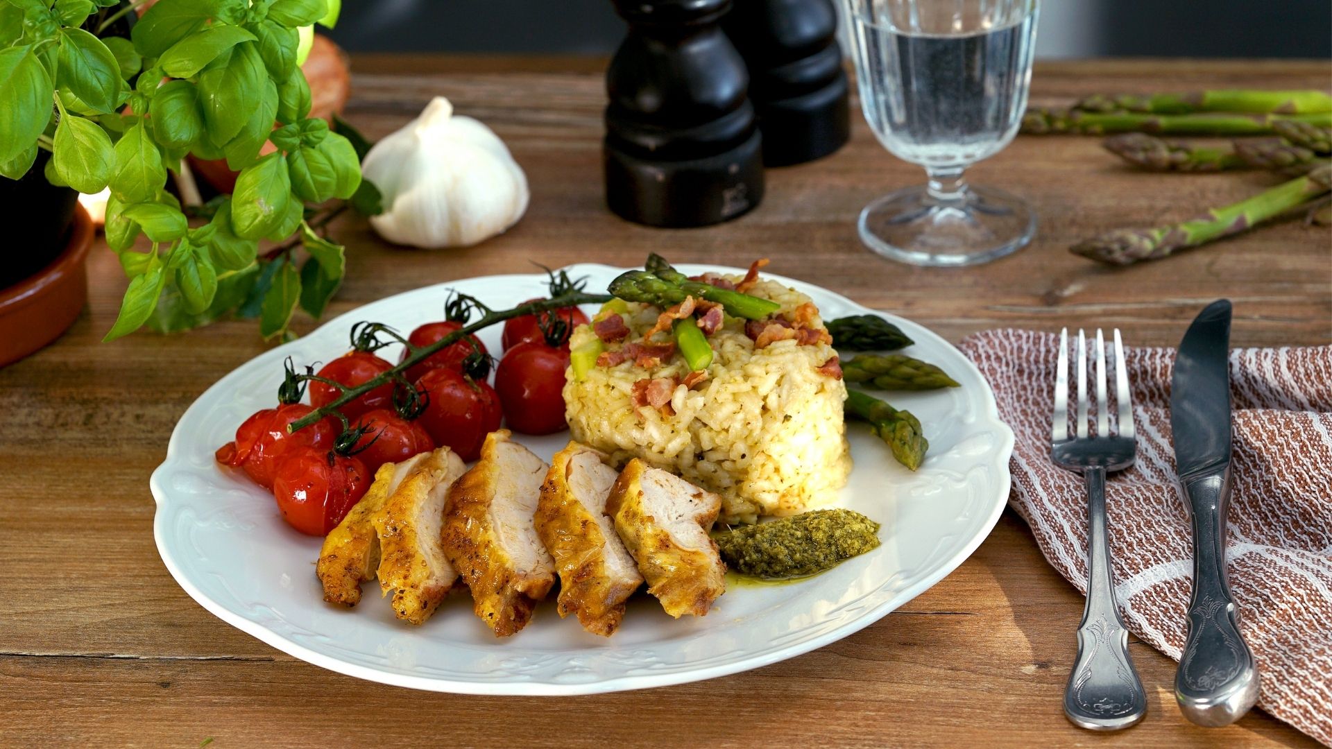 Ein Teller mit einem Tomatenzweig, Risotto und in Scheiben geschnittenem Huhn