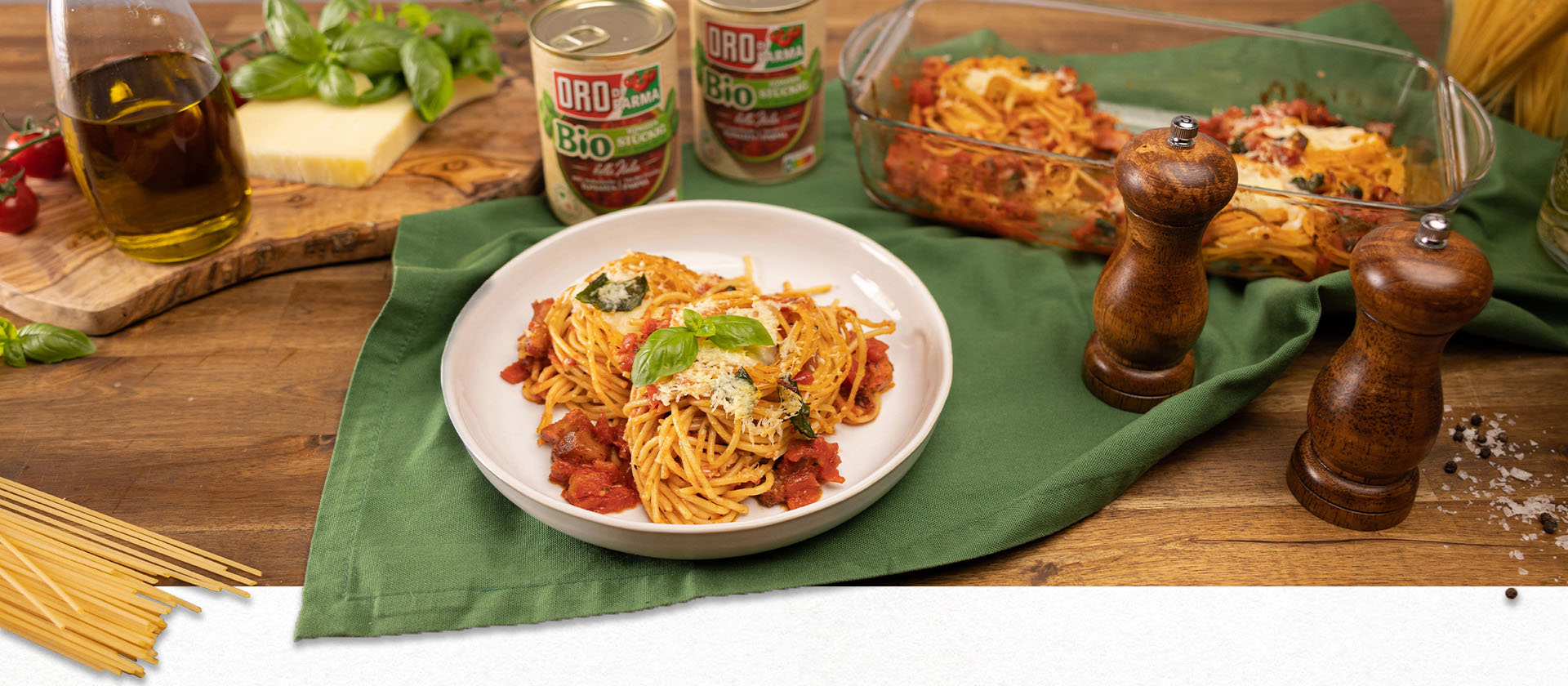 Ein Tisch mit Nudeln, Kräutern und Spaghetti con Provolone e Guanciale in einer Auflaufform aus dem Ofen